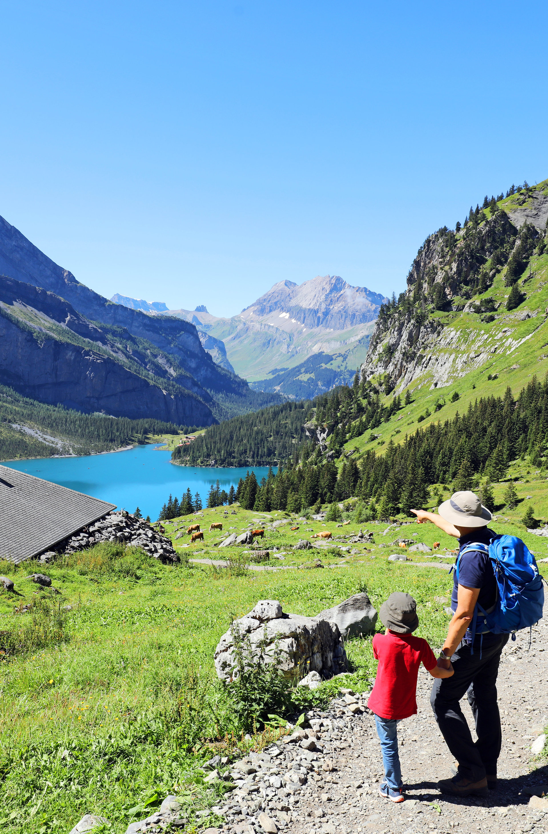 Wanderer mit Kind mit Ausblick auf Berge und einen See